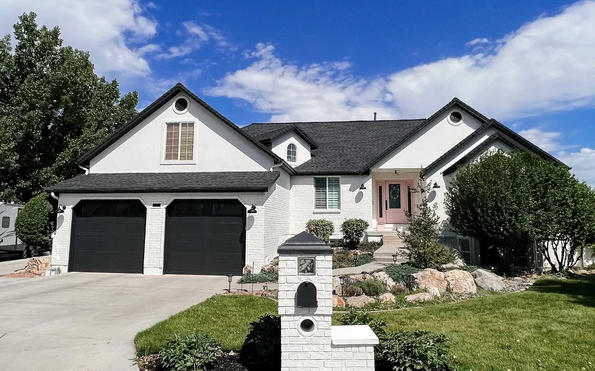 White painted rambler home with dark garage doors